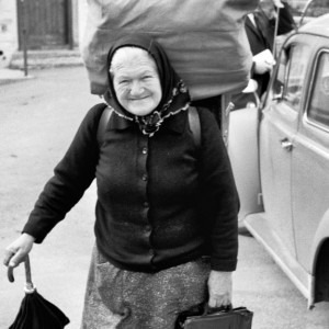 Rosa PANTE from LA MONG (Belluno district, Veneto, Italy), Via Campagna. Italian migrant trader before starting their sales tour in Innerferrera, Avers Valley (Graubünden, Switzerland). The merchandise bears the traveling trader in the box (trucha) on her back. (taken on 26 May 1970).